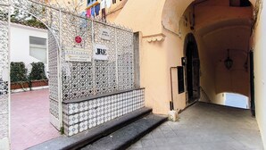 Un callejón estrecho que conduce a un edificio con una reja metálica y un cartel que indica un restaurante y un bar.