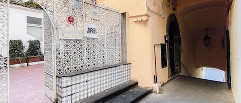 A narrow alleyway leading to a building with a metal gate and a sign indicating a restaurant and a bar.