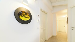 Un pasillo con paredes blancas, una obra de arte redonda y una puerta.