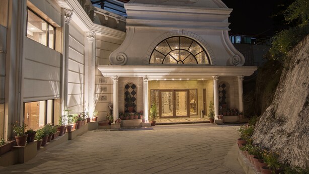 A grand hotel entrance with a large arched doorway, columns, and potted plants. - Hotel Grand Imperial Resort & Spa (Dehradun)