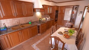 Una cocina con armarios de madera, un lavamanos y una zona de comedor con sillas y una mesa lista para una comida.