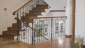 Una escalera de madera con barandillas de metal negro ornamentado y un pasamanos de madera.