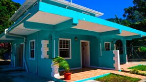 Una casa de dos pisos con fachada azul y un porche de madera.