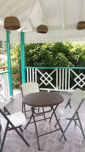 A covered patio area with a round table and four chairs. - Amazon Villas (Soufrière)