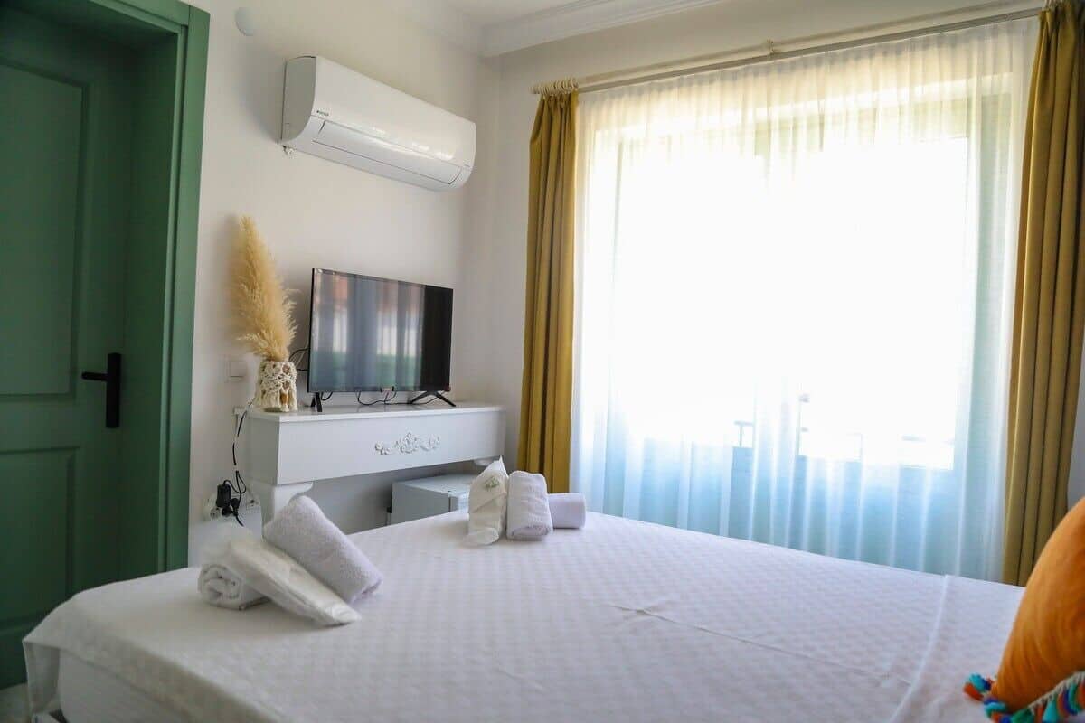 Ein Hotelzimmer mit Bett, Fernseher, Klimaanlage und einem Fenster mit Vorhängen.