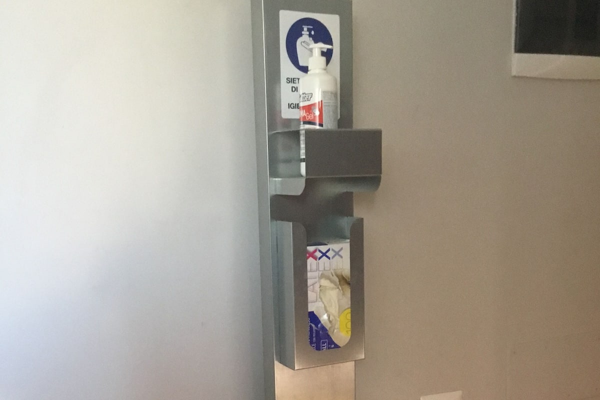 Dispensador metálico fijado a la pared con bomba y caja de pañuelos.