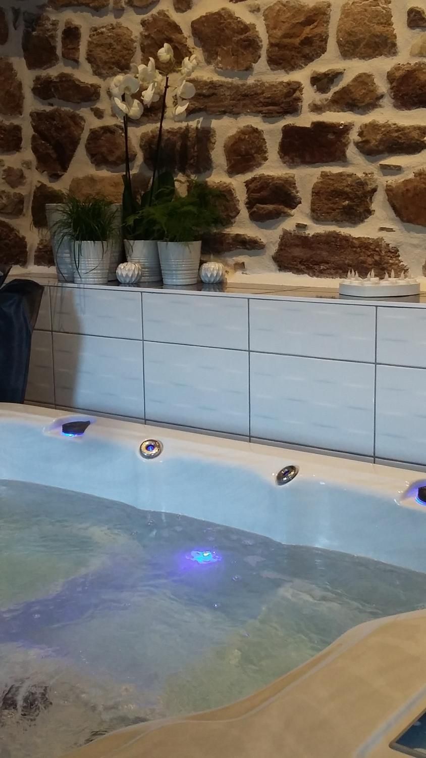 A spa area with a stone wall, a tiled bench, and a hot tub with LED lights.