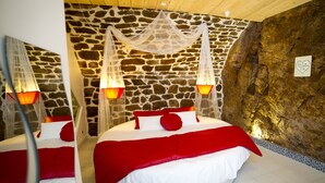 A bedroom with a stone wall, a bed with red and white bedding, and two bedside lamps. - La Cazette (Severac-d'Aveyron)