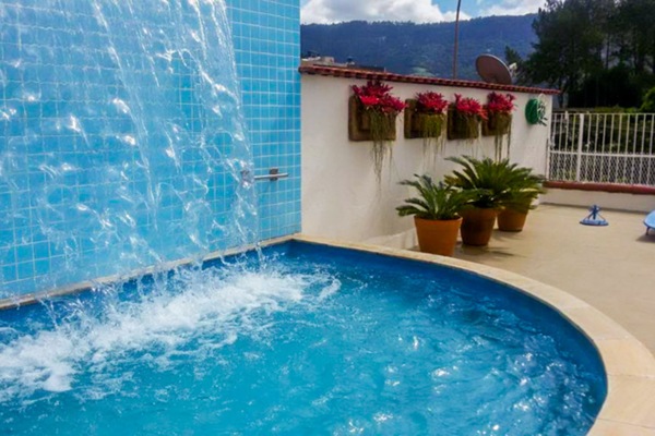 Una piscina al aire libre, sombrillas, sillones reclinables de piscina