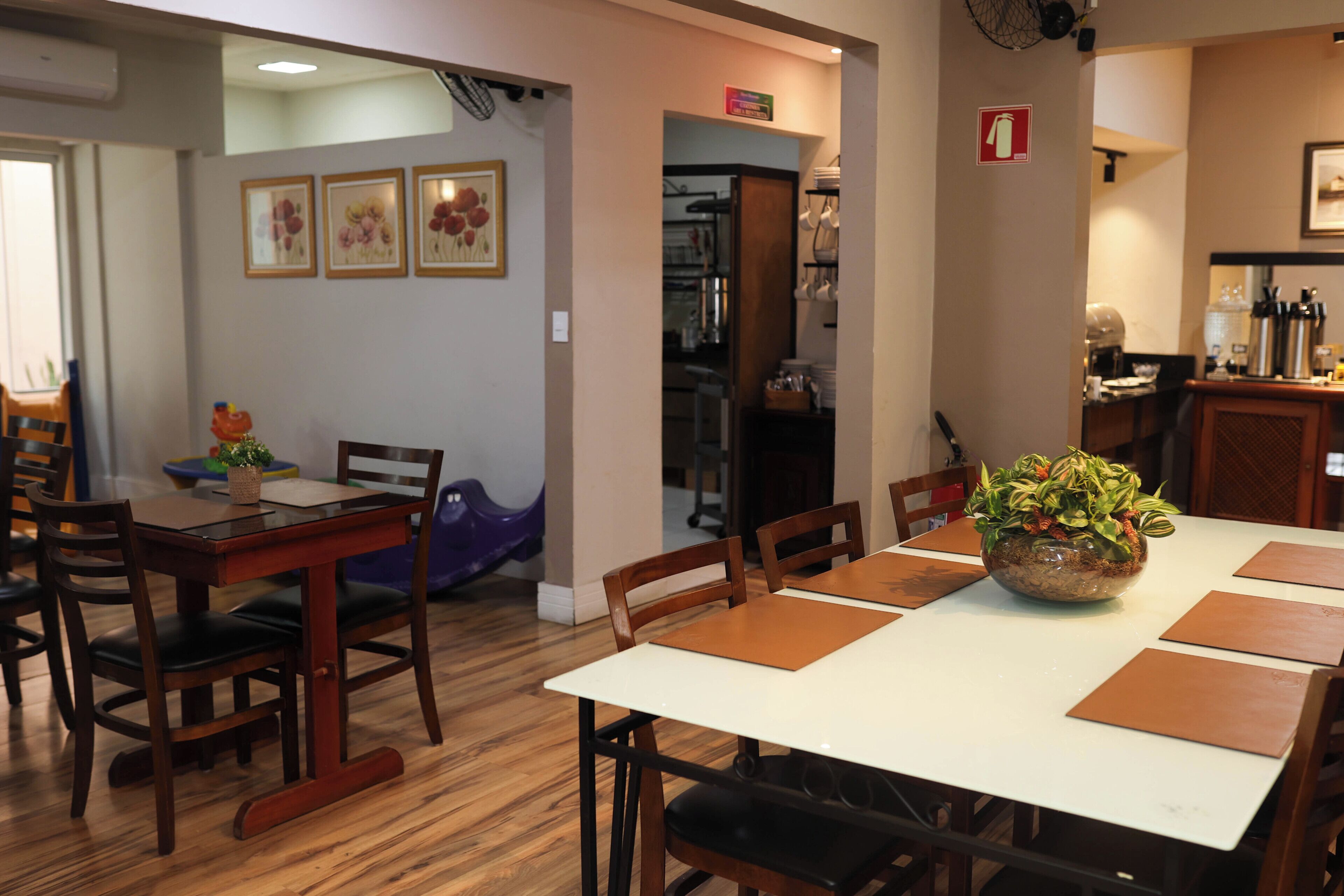 A dining area with a white table, wooden chairs, and a potted plant.