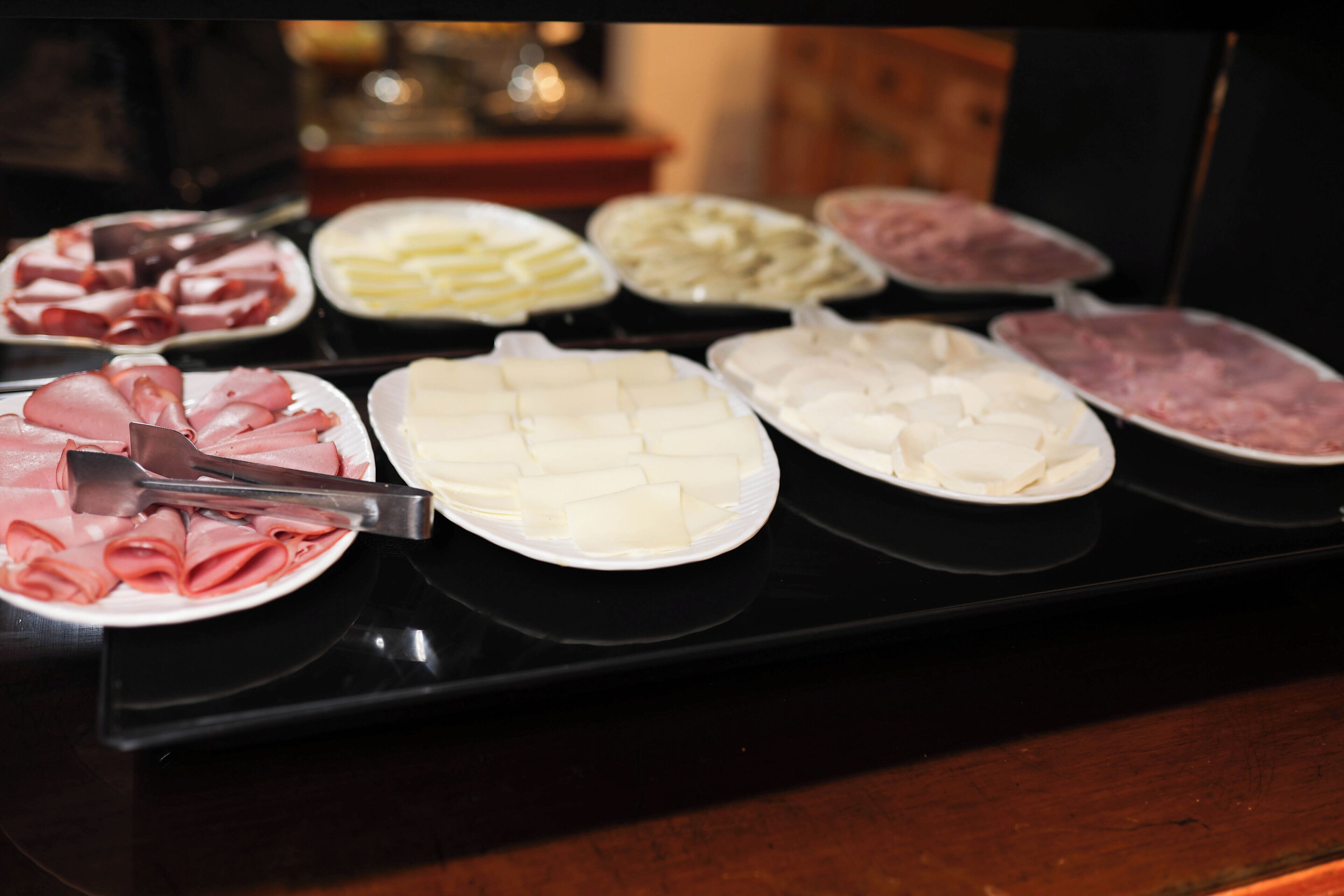 A buffet with various food items including sliced meats and cheeses.