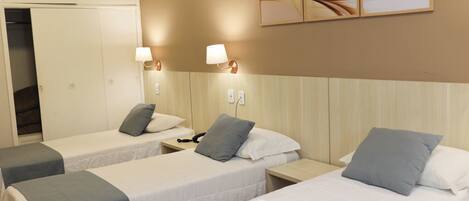 A hotel room with two single beds, a wooden headboard, bedside lamps, a telephone, and a wall-mounted artwork.