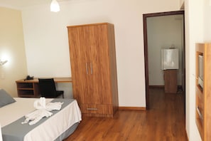 Un dormitorio con cama, armario de madera, escritorio y televisión.