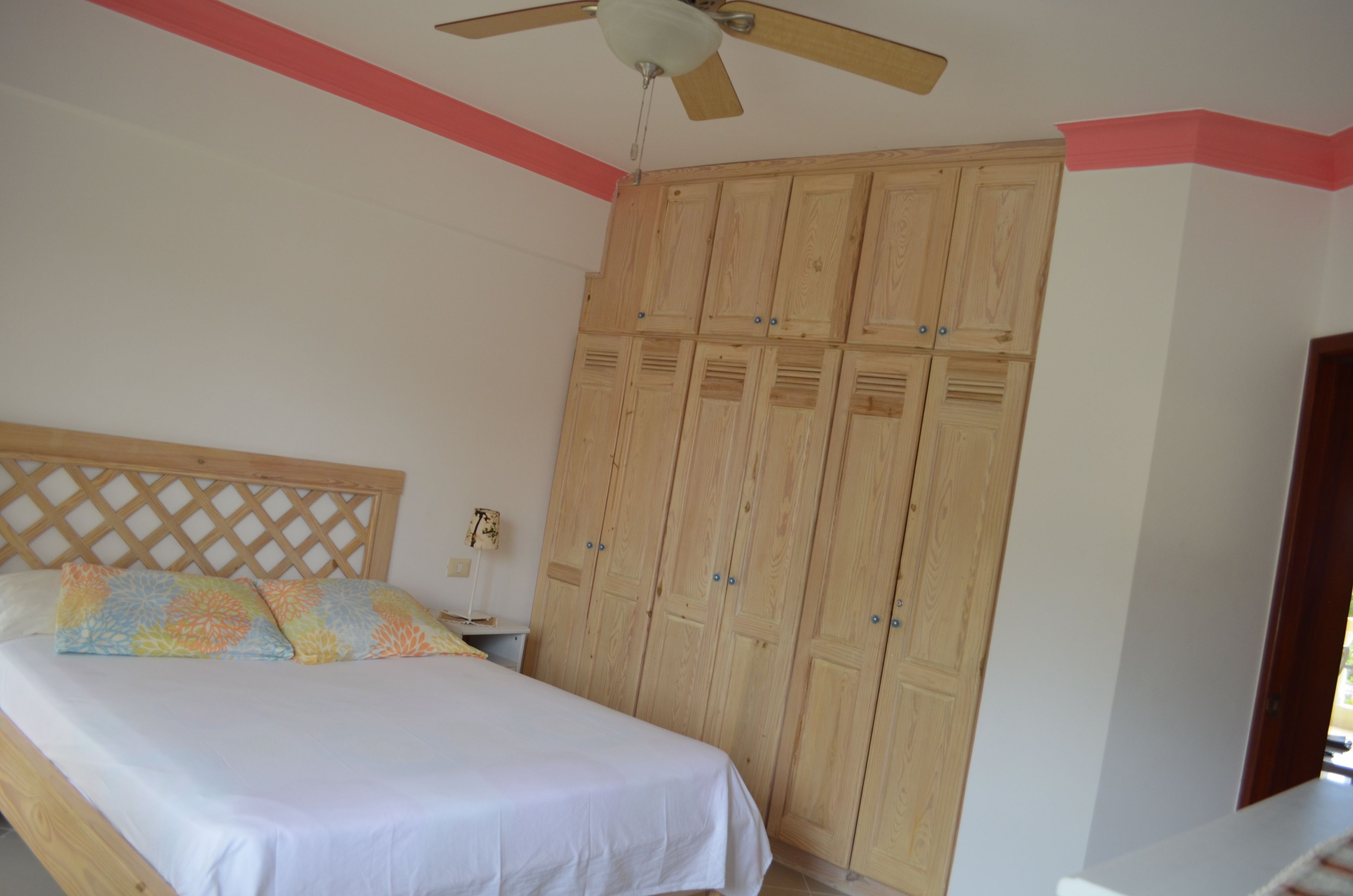 Un dormitorio con cama, armario de madera y ventilador de techo.