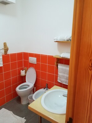 A bathroom with a toilet, sink, and shelves with towels. - Las Palmeras I Mamajo & Riki (Boca Chica)