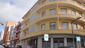 A multi-story yellow building with balconies, a parking sign, and a pedestrian crossing sign. - Apartment with 2 bedrooms in Lisbon (Lisboa)