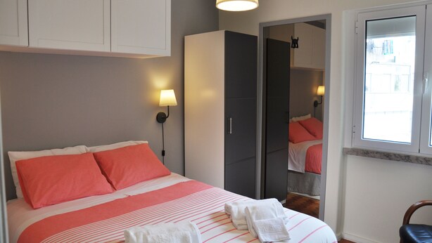 A bedroom with a bed, a wardrobe, a mirror, and a window. - Apartment with 2 bedrooms in Lisbon (Lisboa)