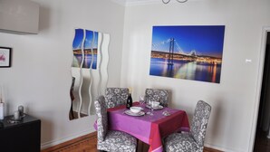 A dining area with a table set for four, a decorative mirror, and two framed pictures of a bridge at night. - Apartment with 2 bedrooms in Lisbon (Lisboa)