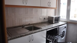 A kitchen with white cabinets, a granite countertop, a microwave, a sink, and a dishwasher. - Apartment with 2 bedrooms in Lisbon (Lisboa)