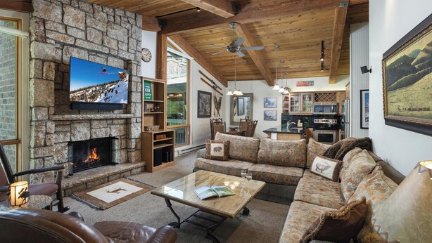 Ein gemütliches Wohnzimmer mit Kamin aus Stein, Fernseher und Sofa.
