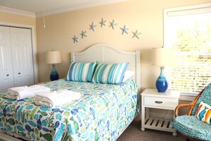 Une chambre à coucher avec un lit, deux tables de chevet, une chaise et un mur décoré d’étoiles.