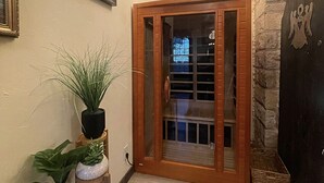 Un pasillo con puerta de madera, un candelabro y plantas en macetas.