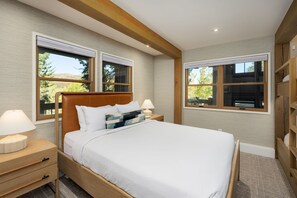 Een slaapkamer met een groot bed, twee nachtkastjes en een bedbank. Aan beide kanten van het bed bevinden zich ramen.