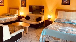 Habitación de hotel con dos camas, un sofá, una mesita y un espejo.