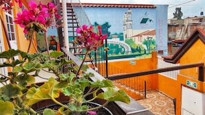 Una escalera con un mural que muestra un puente y una iglesia, rodeada de plantas en macetas.