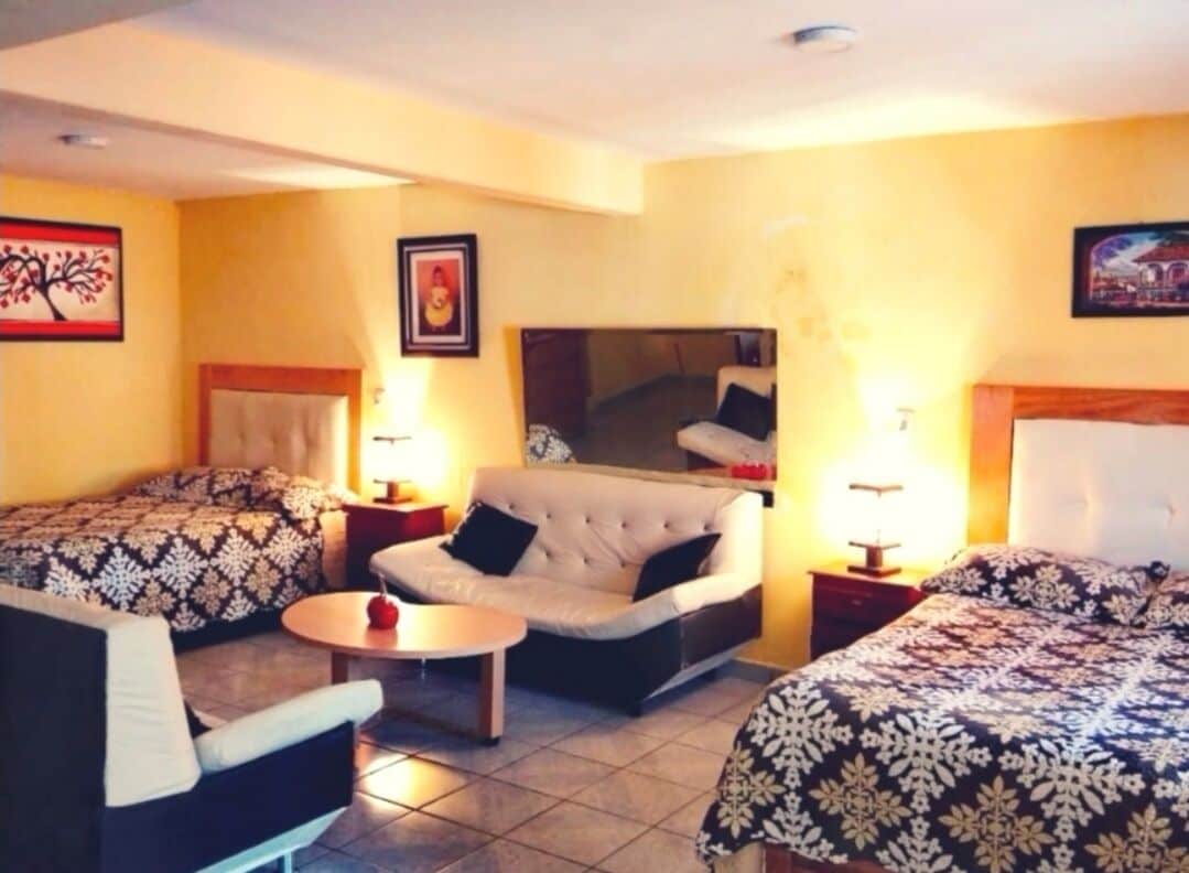 Een hotelkamer met twee bedden, een bank, een kleine tafel en een televisie.
