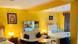 Habitación de hotel con dos camas, un sofá, una mesita y un espejo.