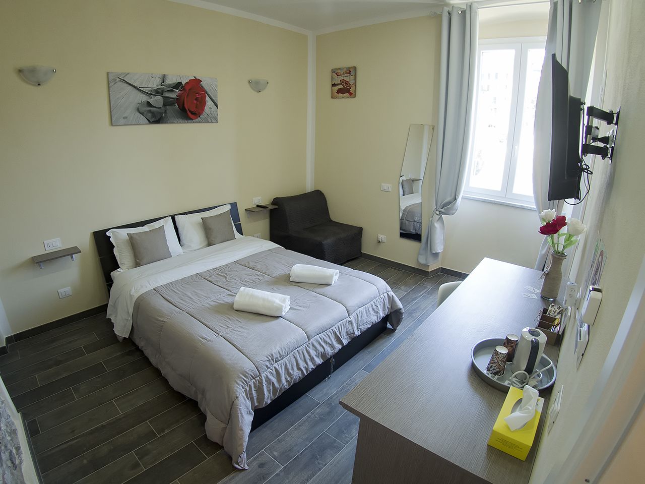 A hotel room with a bed, a chair, a desk, and a TV.