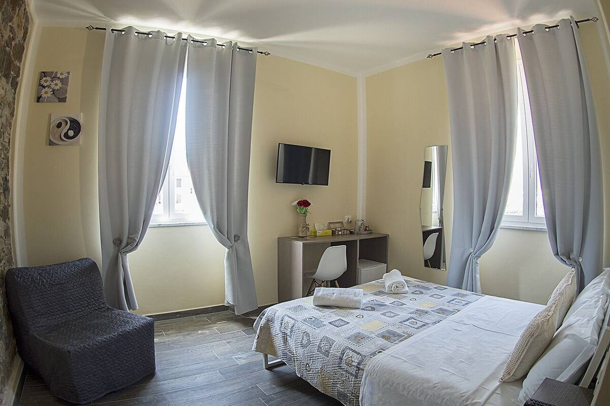 Ein Schlafzimmer mit Bett, Stuhl, Schreibtisch und Fernseher.