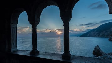 Vista a través de arcos de piedra sobre un mar tranquilo al atardecer.