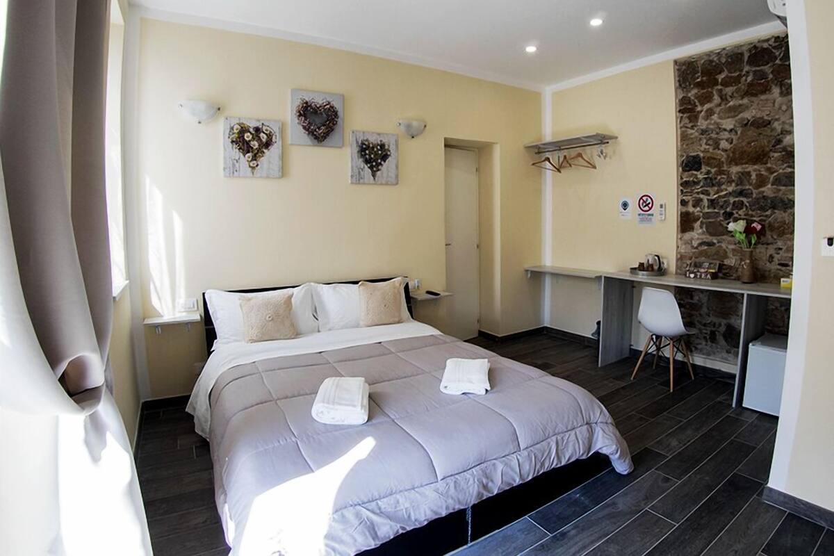 Ein Schlafzimmer mit einem Bett, einem Schreibtisch und einer Steinwand.