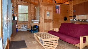 L’intérieur d’un chalet en bois comprend une table à manger en bois, un canapé rouge et un coin cuisine.