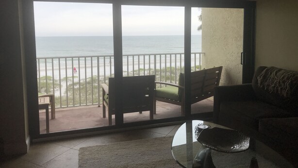 Una stanza con una porta in vetro che dà su un balcone con vista sulla spiaggia.
