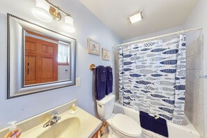 A bathroom with a sink, toilet, and shower curtain with a fish pattern. - White Wing Resort (Branson)