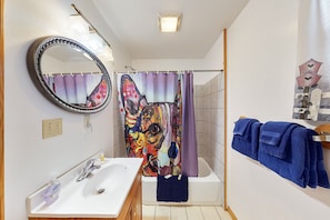 A bathroom with a white sink, mirror, and shower curtain with a colorful design. - White Wing Resort (Branson)