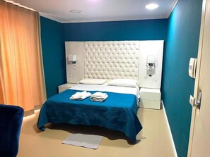 A hotel room with a large bed, two bedside tables, a headboard, and a curtain. - Napoli Centro (Naples)