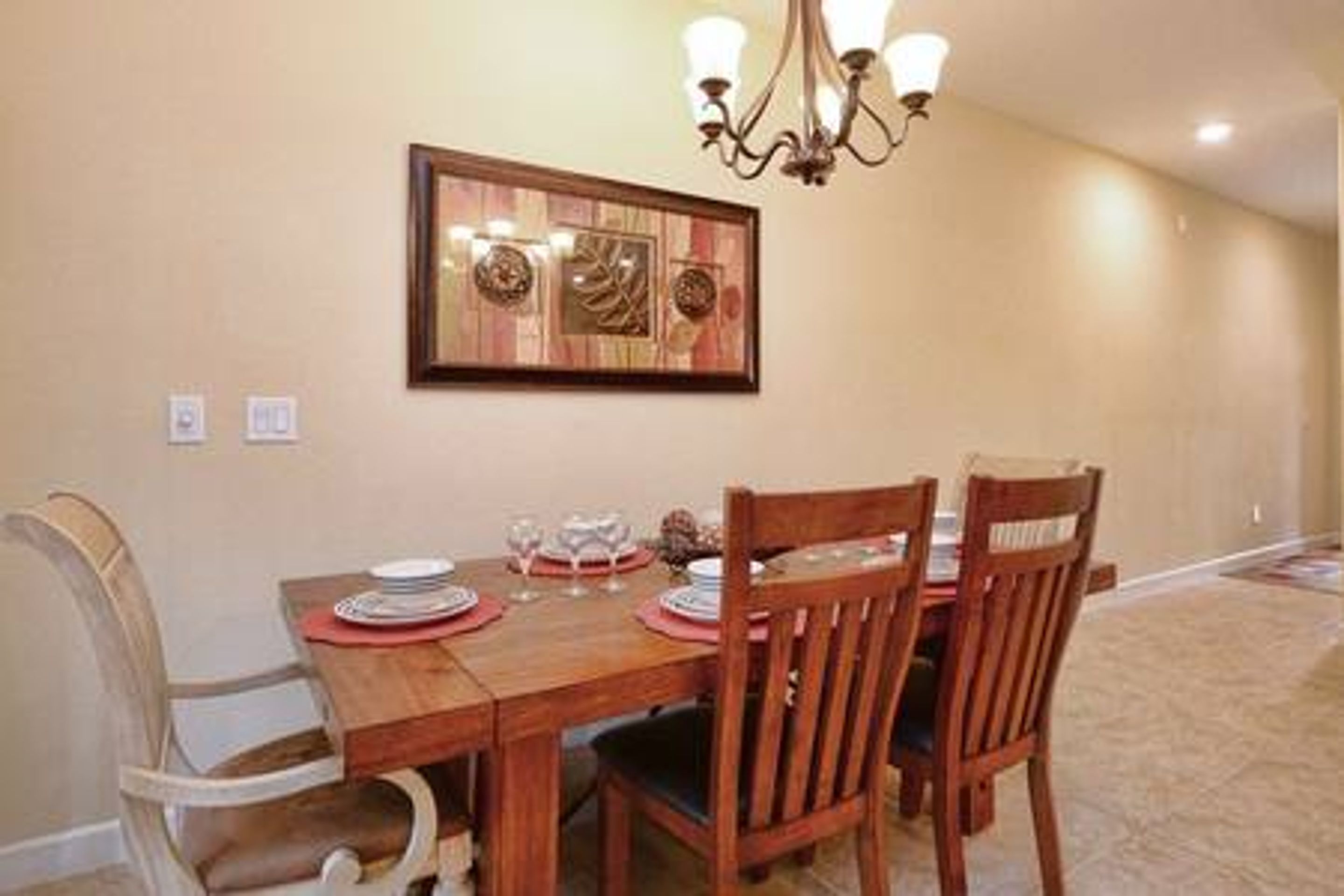 A dining area with a wooden table, four chairs, and a chandelier.