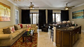Un salón amplio con sofá, una mesa de centro y una zona de cocina con fregadero y armarios.
