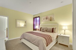 A bedroom with a bed, nightstand, lamp, and a mirror on the wall.