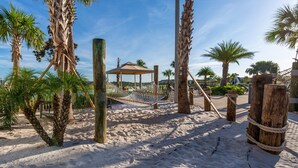 A sandy beach area with palm trees, a hammock, and a wooden structure. - Storey Lake 4813 (Kissimmee)
