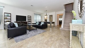 A modern living room with a black sofa, a television, and a staircase leading to another level. - Watersong Resort 427 (Davenport)