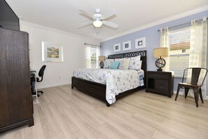A bedroom with a bed, nightstands, a chair, a desk, and a ceiling fan. - Watersong Resort 427 (Davenport)