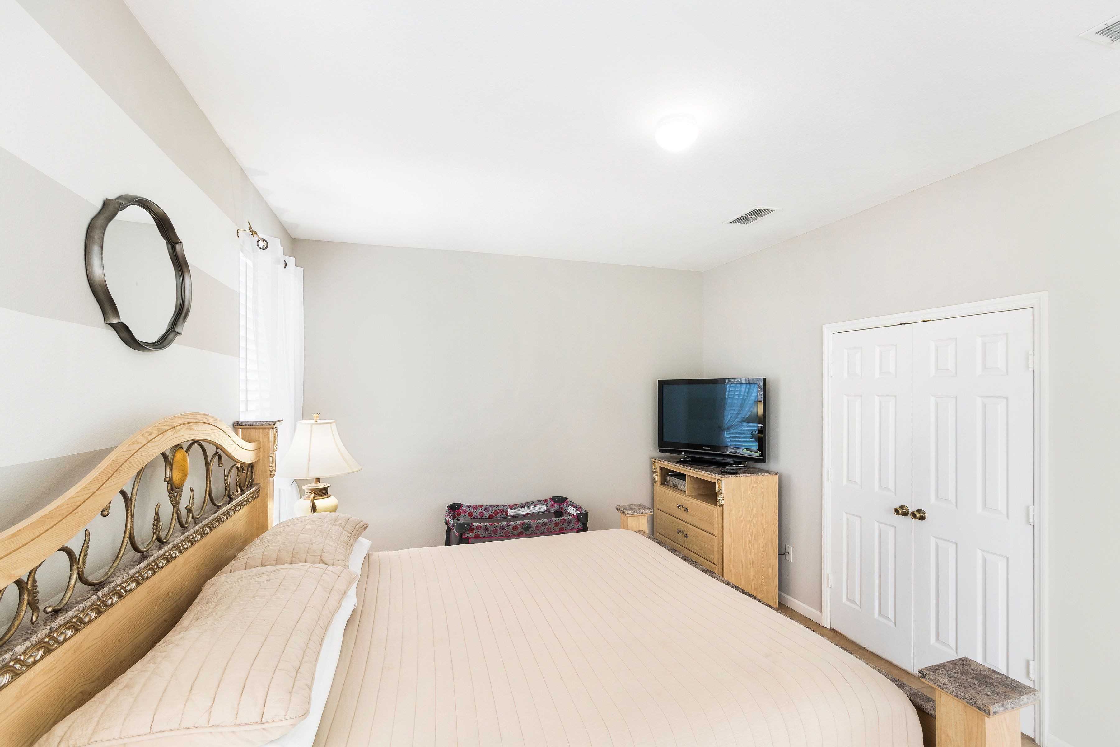 A bedroom with a bed, a television, a dresser, and a door.