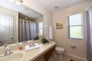 A bathroom with a sink, mirror, toilet, and shower curtain. - Regal Palms Resort & Spa at Highlands Reserve 2530 (Davenport)