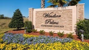 A sign for Windsor Palms A Gated Resort Community with a stone facade and a landscaped garden with flowers. - Windsor Palms Resort 2357 (Kissimmee)