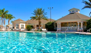 A swimming pool with clear blue water, surrounded by lounge chairs and palm trees. - Windsor Palms Resort 2357 (Kissimmee)